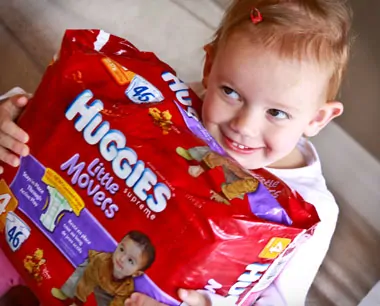 Olivia hugging a packing of Huggies Little Movers diapers