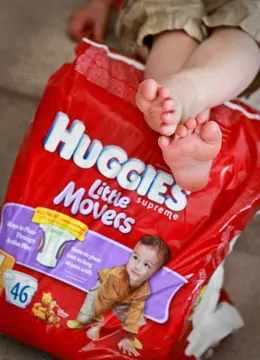 Toddlers feet resting on Huggies diapers 