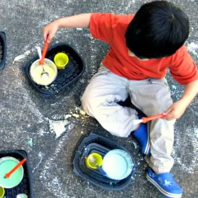 preschooler painting with sidewalk chalk