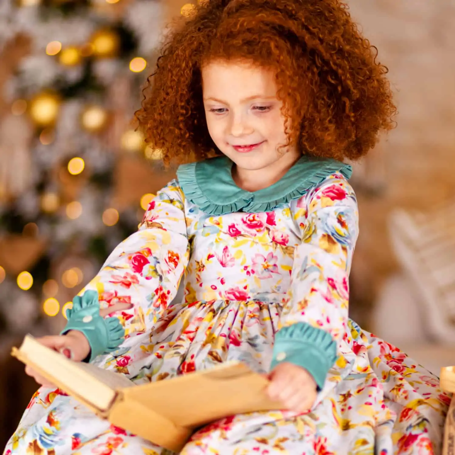 Young girl reading a book next to a Christmas Tree - Theme Giving Books for the Holidays