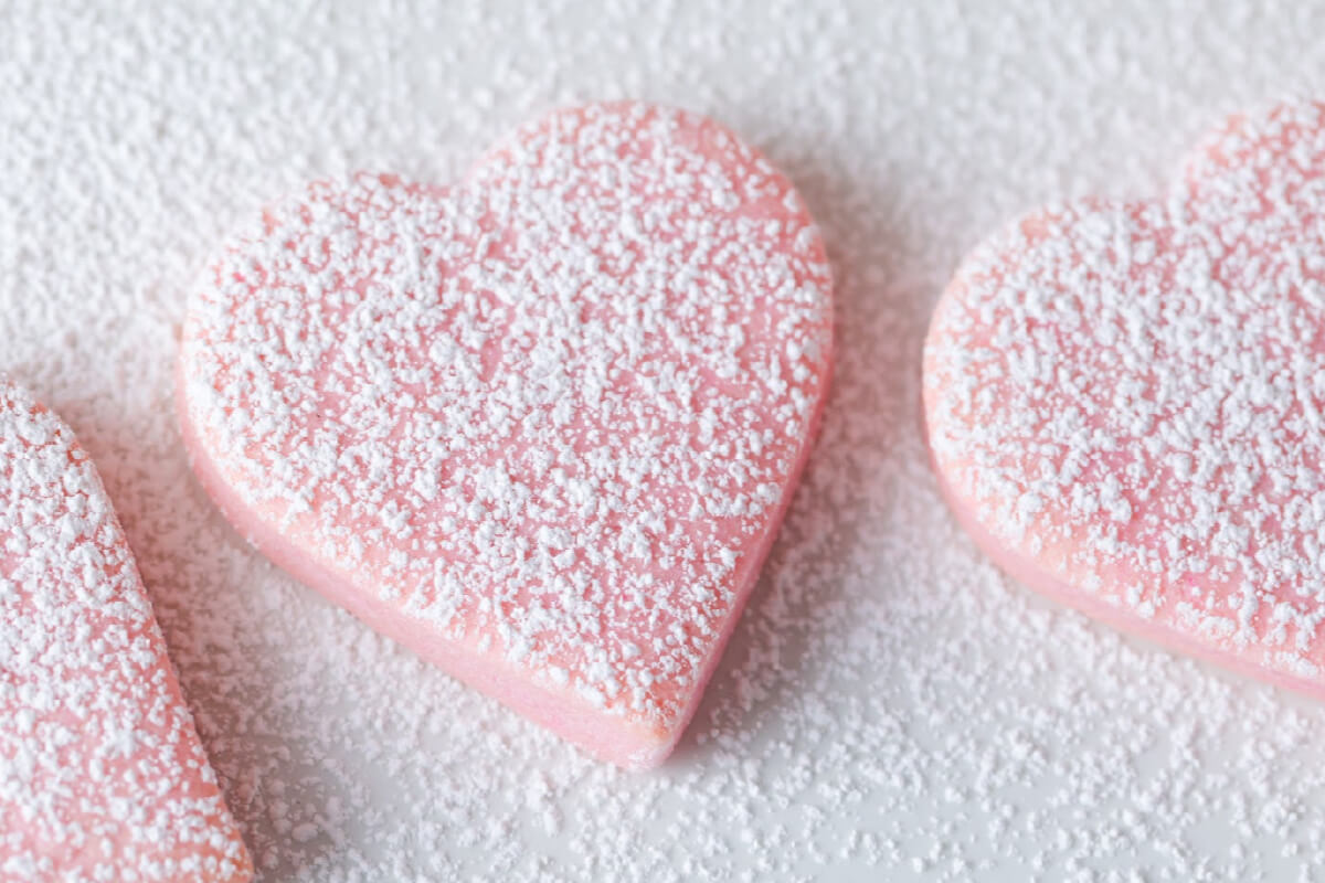 valentine sugar cookies made with pink cookie dough, cut into heart shapes, and sprinkled with powdered sugar