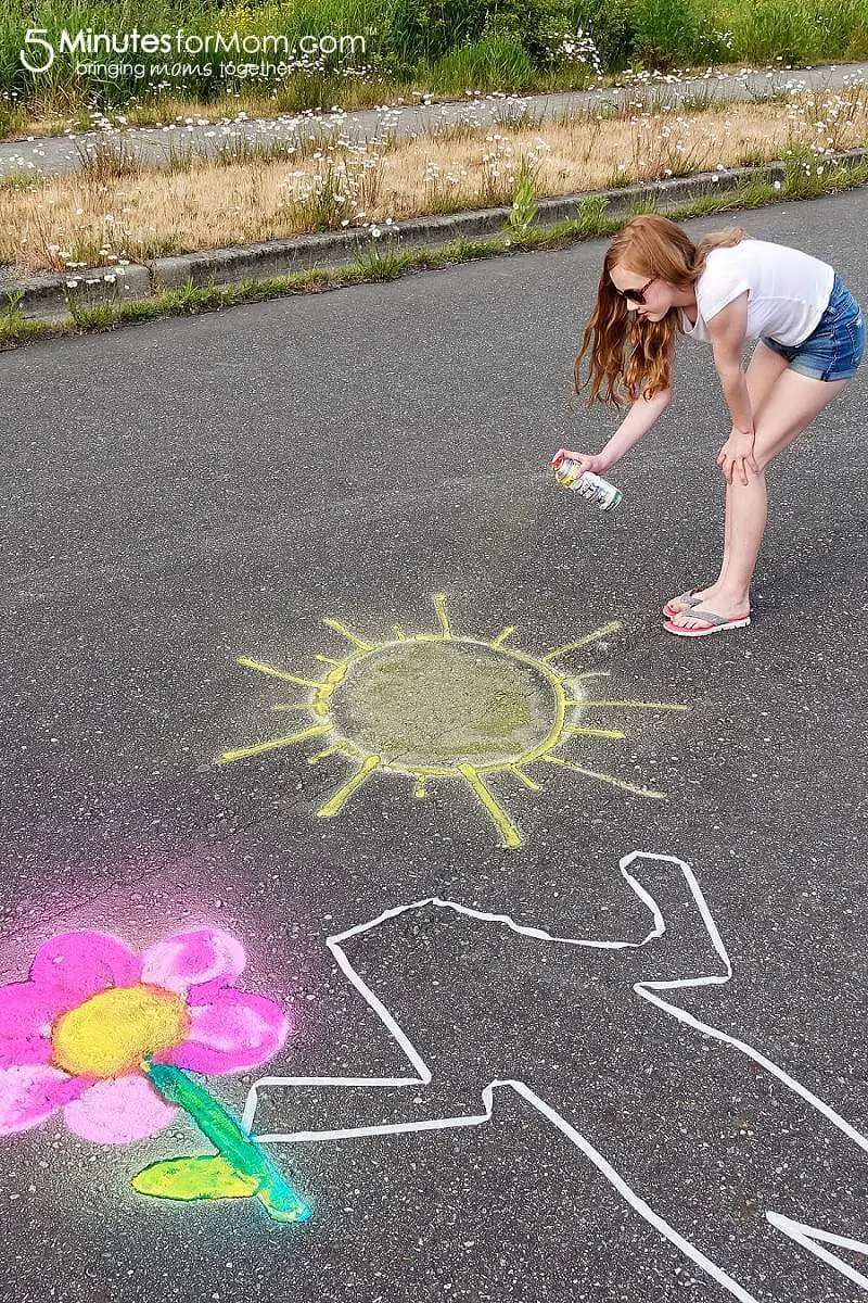 Teenage girl spray chalking sidewalk art