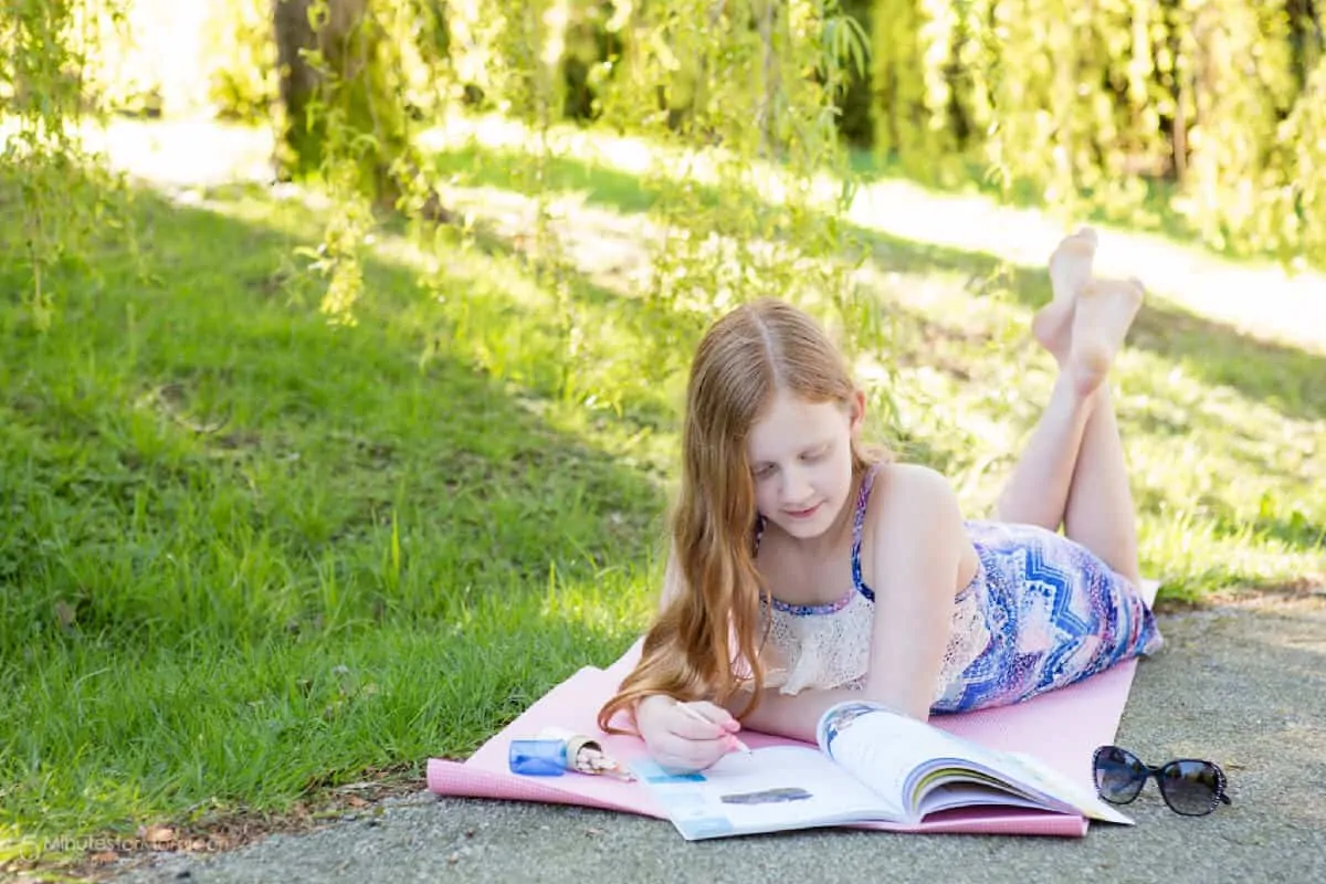 twelve year old girl laying outside on a yoga pad and learning outside