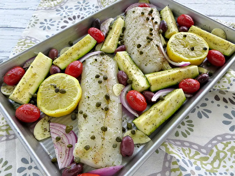 Mediterranean Cod Sheet Pan Dinner. Thinly slicing the garlic and quartering the zucchini ensures that they cook through in the same time as the fish.