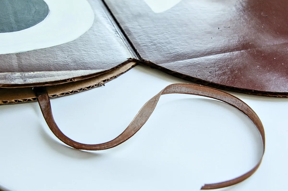 attach brown ribbon to each side of the poop emoji costume that can be tied together to keep the sides closed 