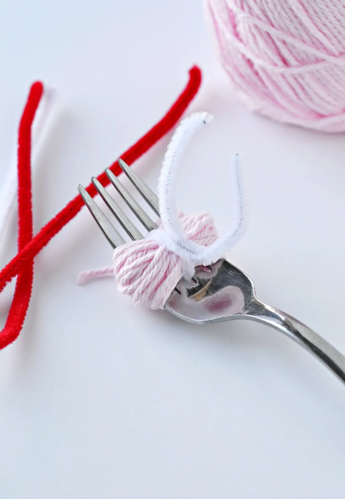 securing the pom pom with a pipe cleaner