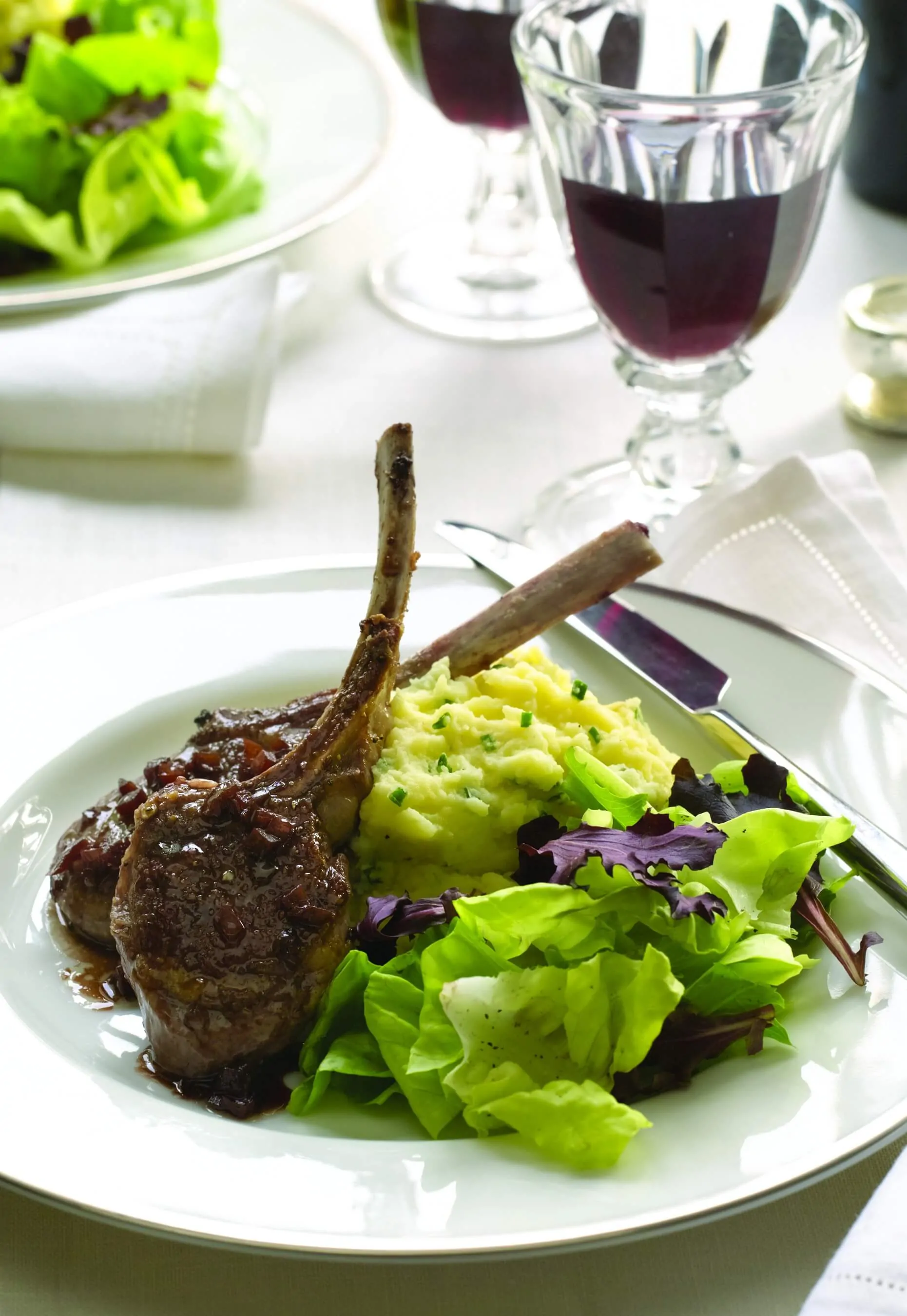 Dinner plate with Baby Lamb Chops with Red Wine Sauce and Garlic Mashed Potatoes along and Greens with White Wine Vinaigrette