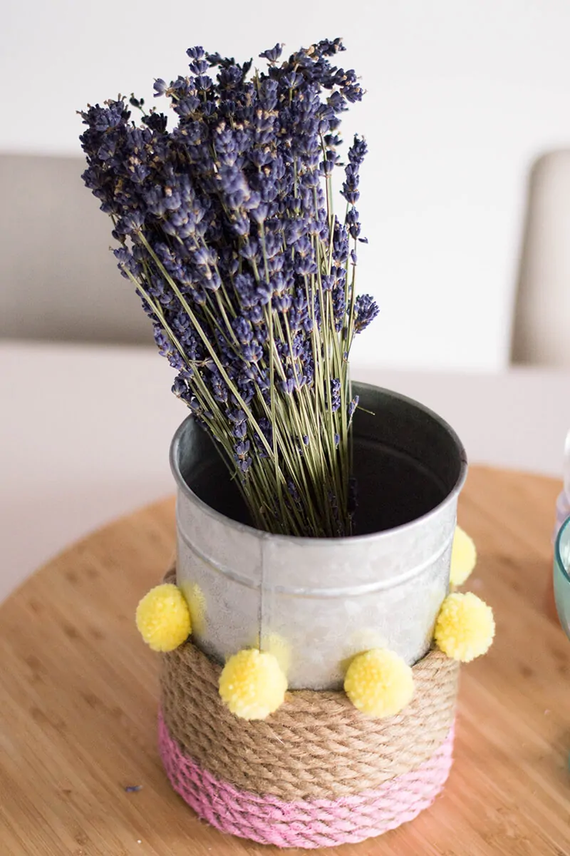 A Rope Vase DIY to add that touch of color to your home. How can you go wrong with pink, pompoms, and a bouquet of flowers?