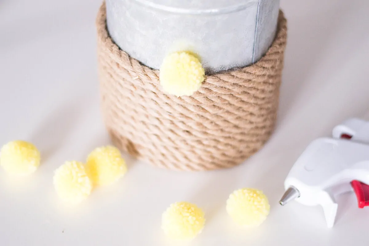 A Rope Vase DIY to add that touch of color to your home. How can you go wrong with pink, pompoms, and a bouquet of flowers?