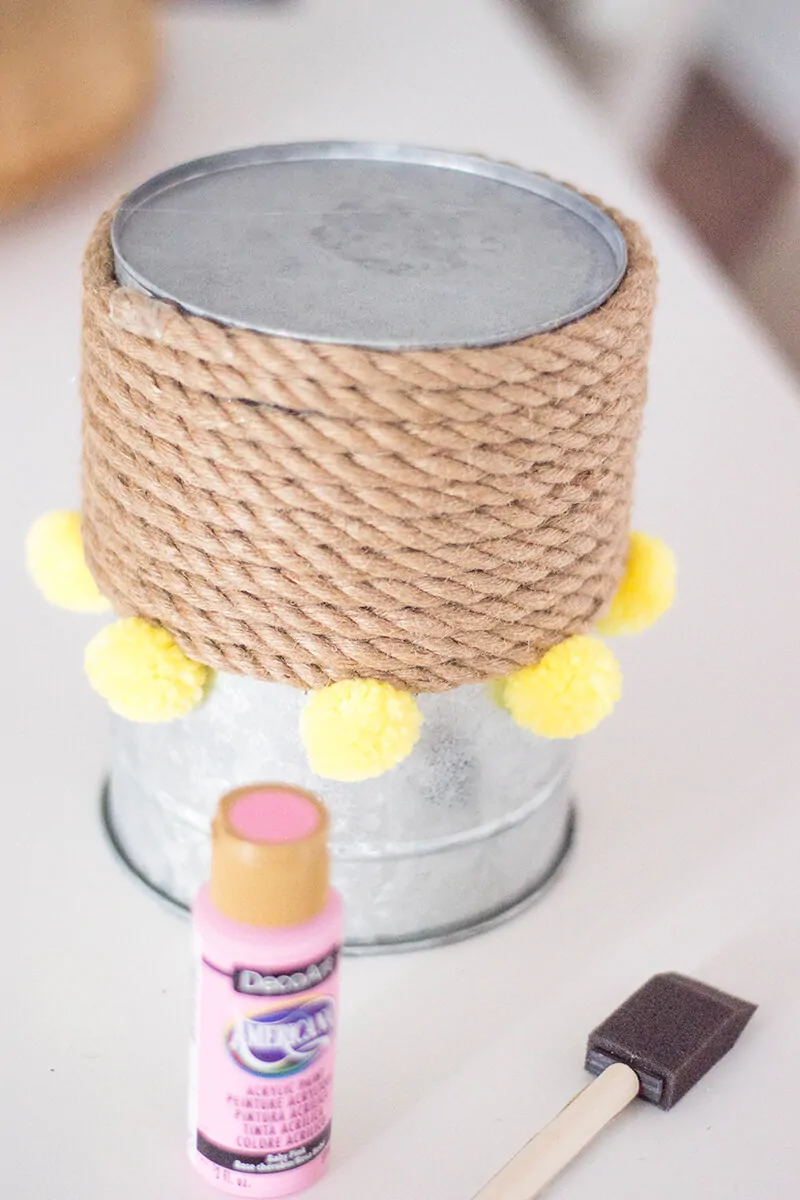 A Rope Vase DIY to add that touch of color to your home. How can you go wrong with pink, pompoms, and a bouquet of flowers?