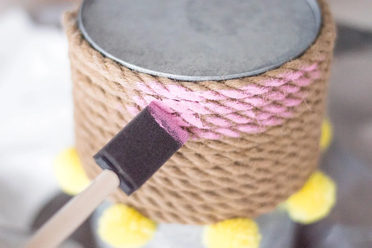 A Rope Vase DIY to add that touch of color to your home. How can you go wrong with pink, pompoms, and a bouquet of flowers?