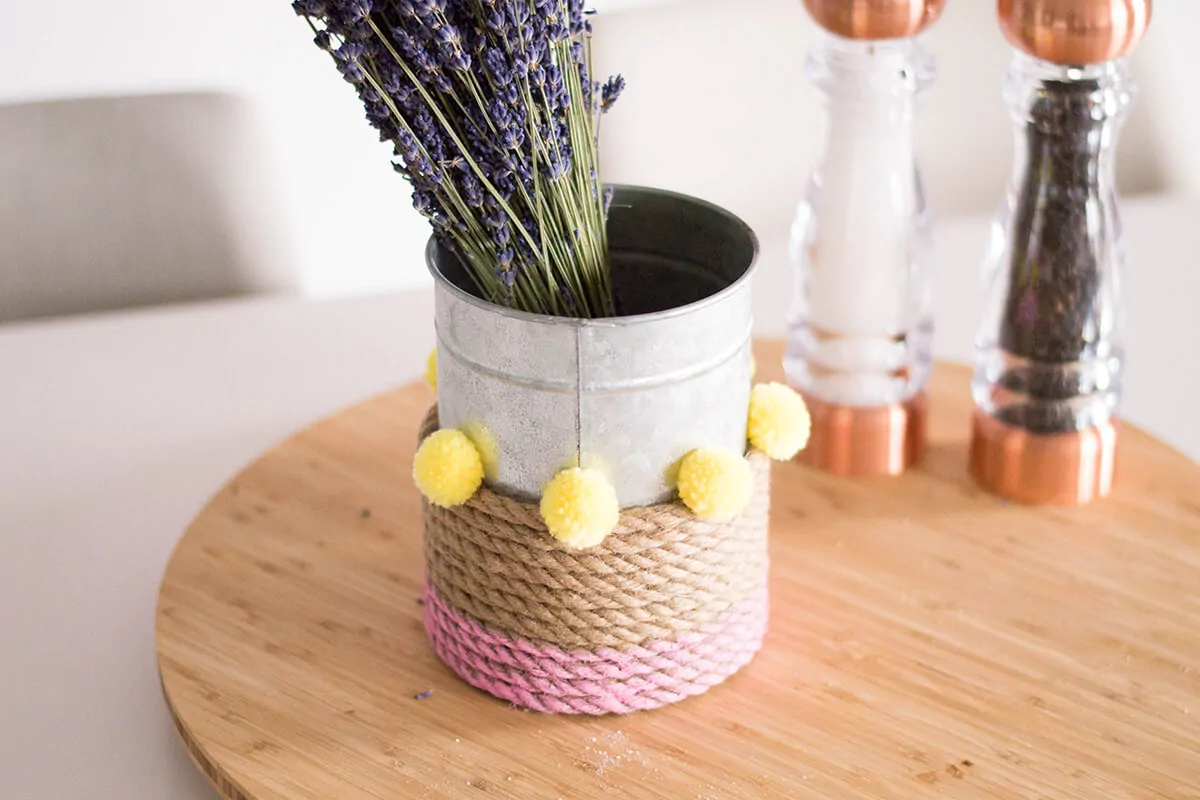 A Rope Vase DIY to add that touch of color to your home. How can you go wrong with pink, pompoms, and a bouquet of flowers?