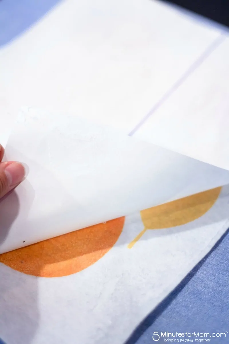 Peeling off transfer paper to show colored leaves on the white felt