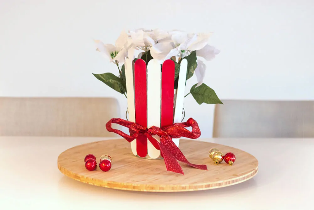 Easy Christmas Centerpiece - White poinsettia in a DIY plant pot made with red and white extra-large popsicle sticks.