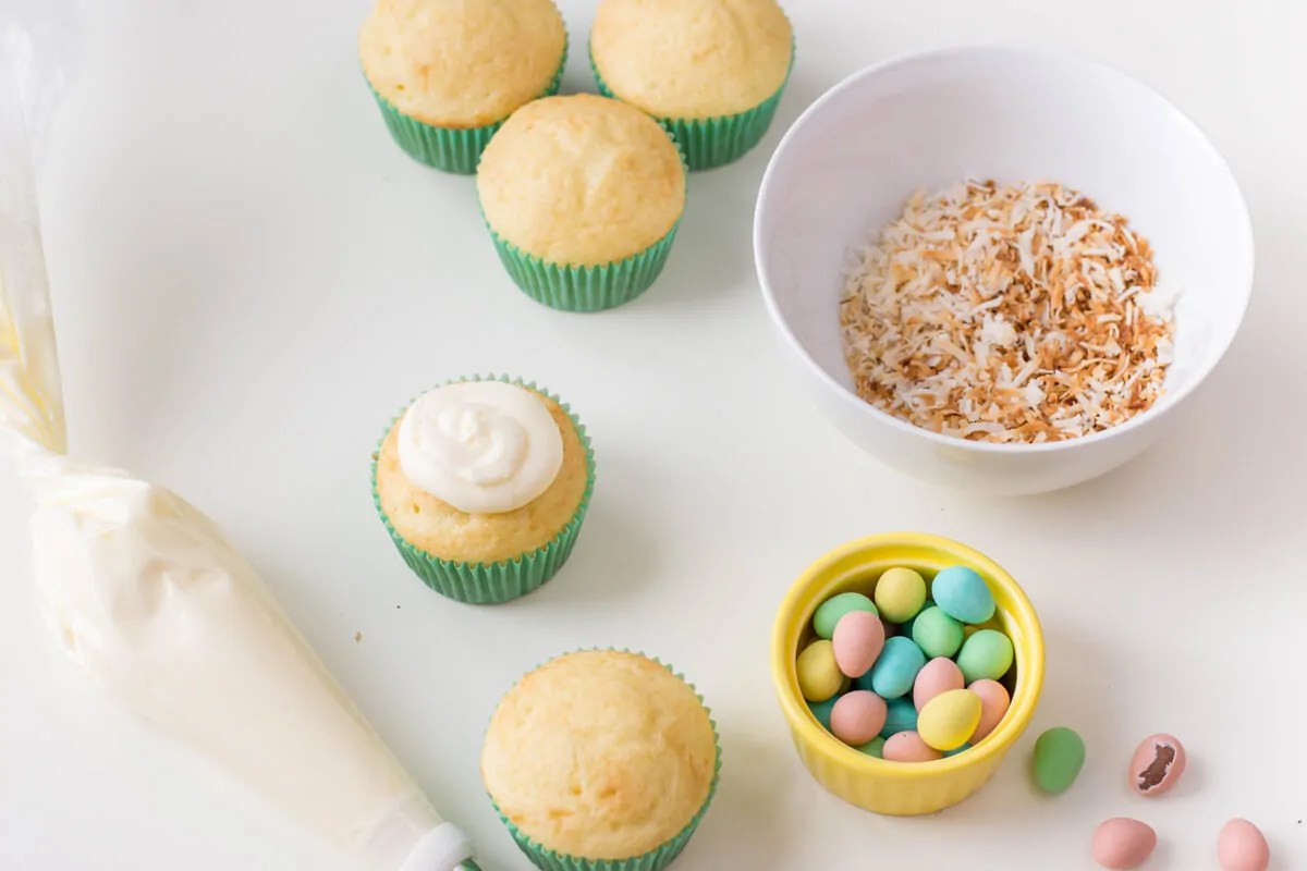 Piping buttercream on vanilla cupcakes to make Bird's Nest Cupcakes