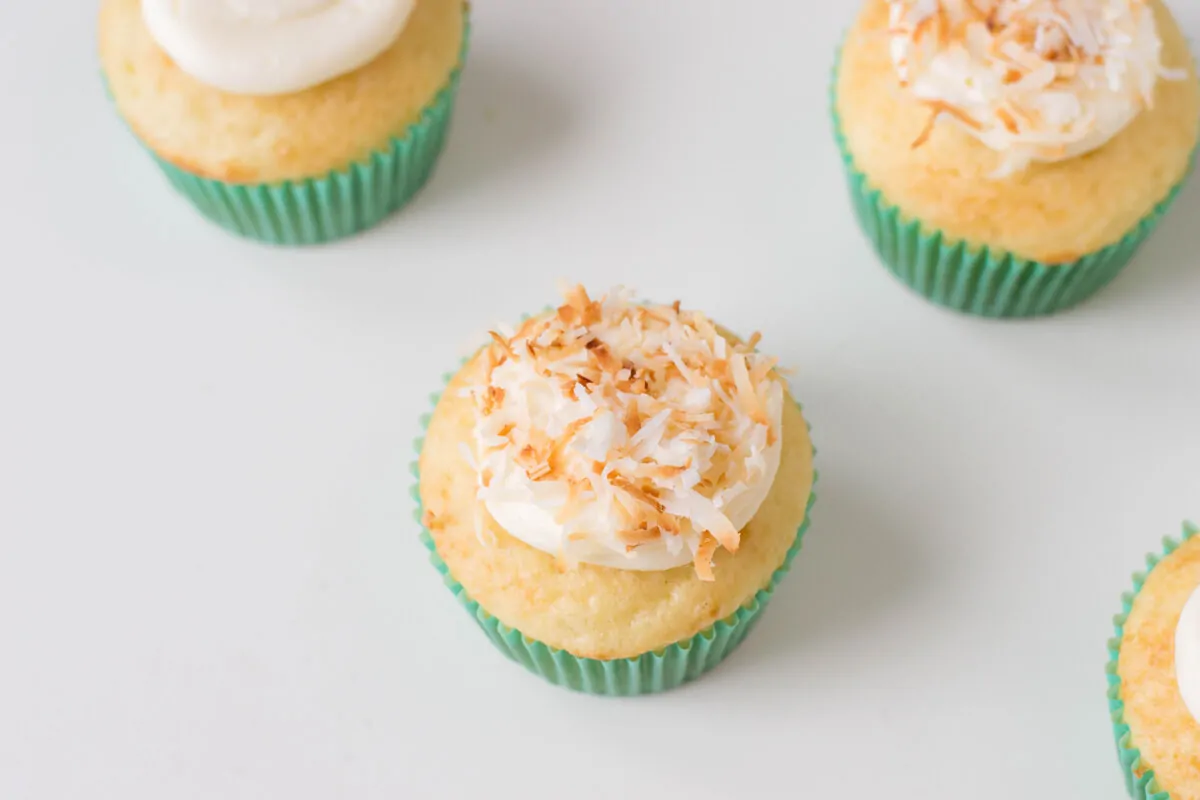 Adding coconut topping to vanilla cupcakes to make Bird's Nest Cupcakes.