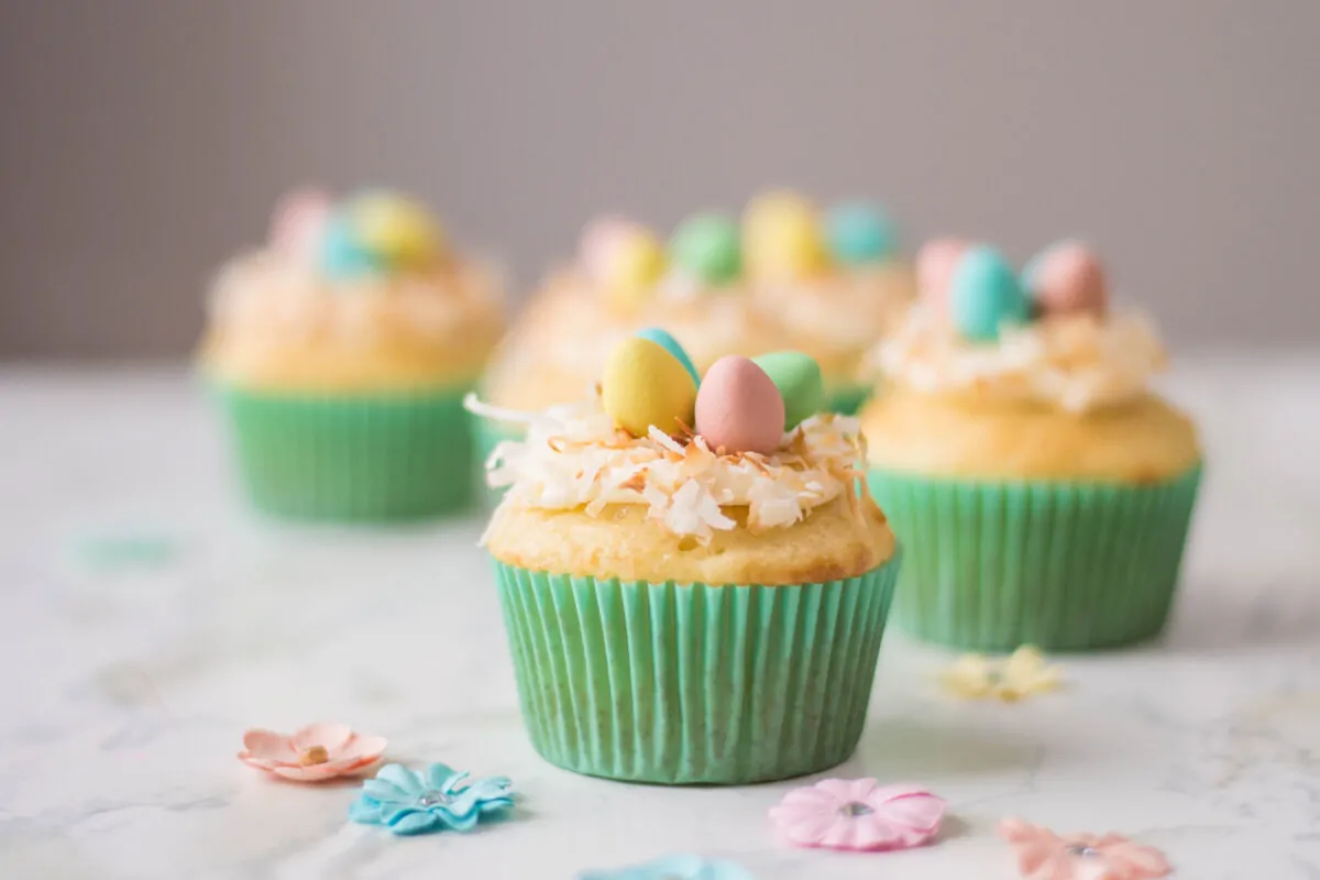 Vanilla cupcakes topped with buttercream, shredded coconut and candied eggs: they make for the perfect Bird's Nest Cupcakes!