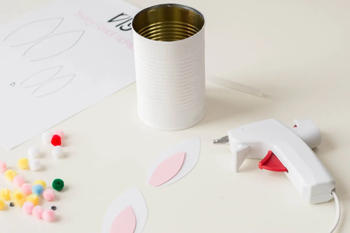 How to use a hot glue gun to attach paper ears to the tin can - Step 1.