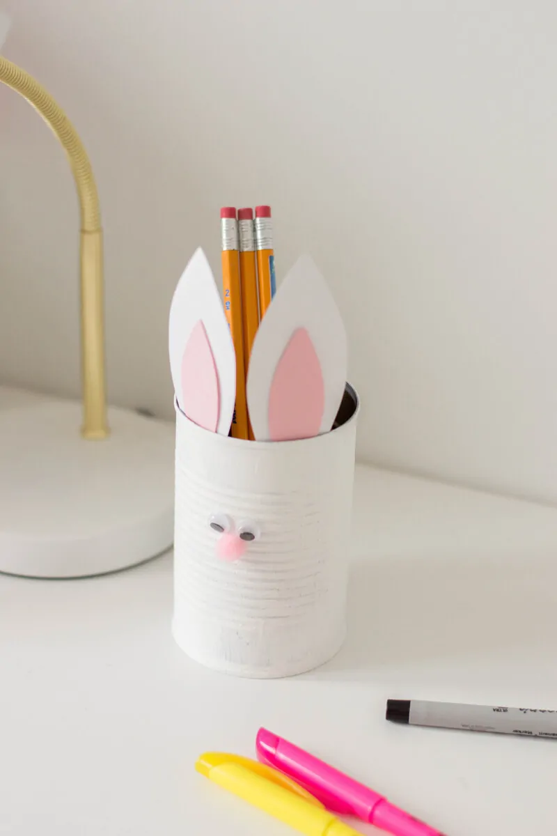 An Easter DIY made of a painted tin can with bunny ears and a pompom nose. Here's our very own Bunny Pencil Holder.