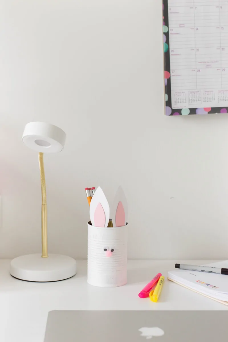 An easy Easter craft for kids. Use a painted tin can with bunny ears and a pompom nose to make a Bunny Pencil Holder.