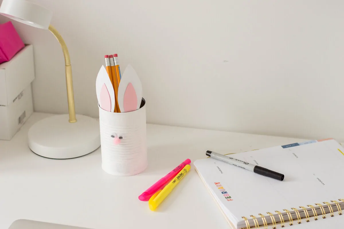 An Easter DIY made of a painted tin can with bunny ears and a pompom nose.