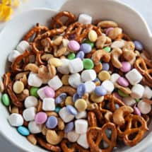 Spring snack mix in white bowl on a white marble background