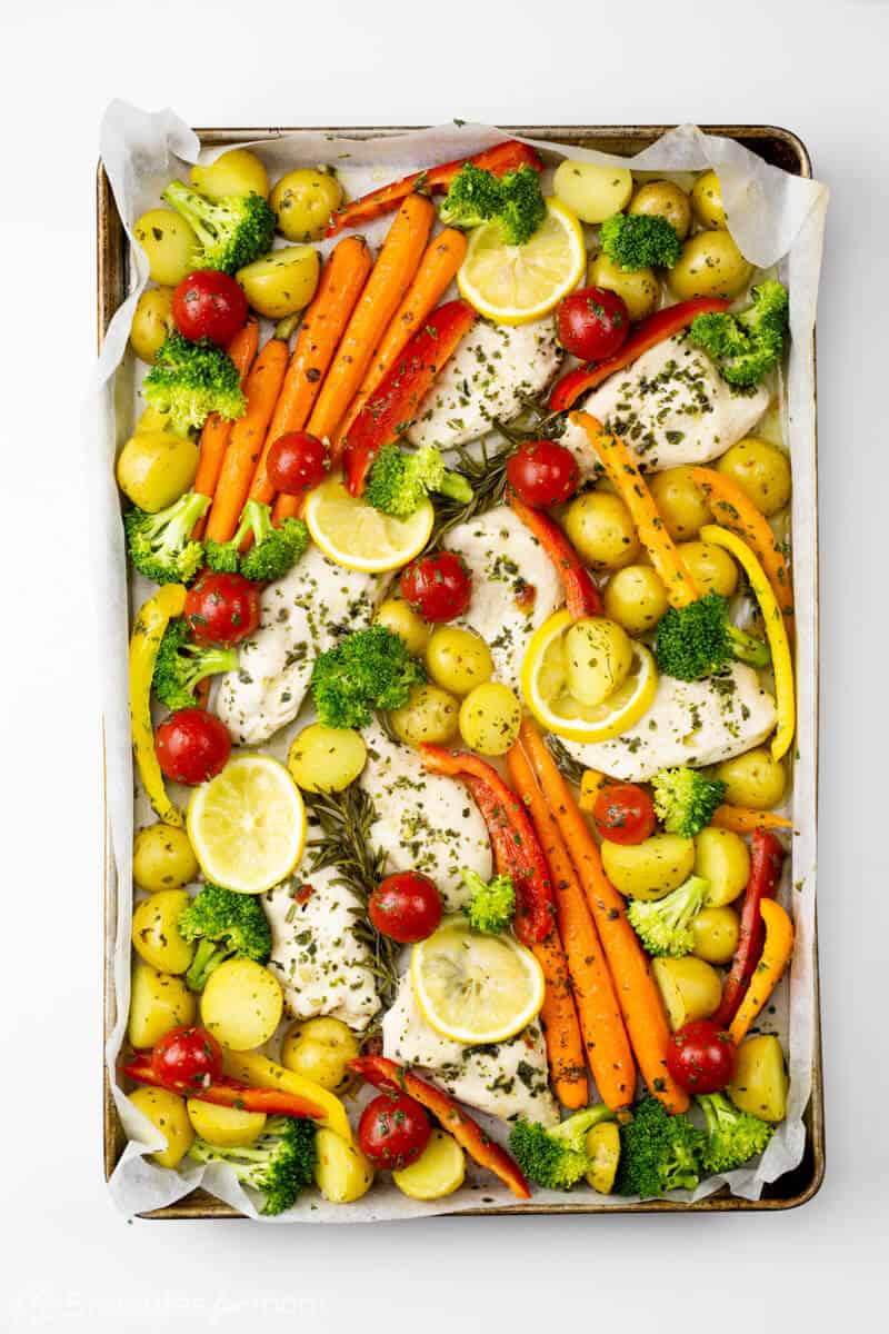Add extra vegetables to partially cooked chicken on the baking pan
