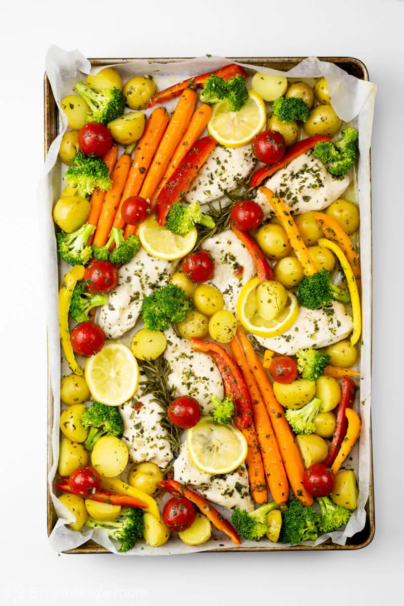 Add extra vegetables to partially cooked chicken on the baking pan