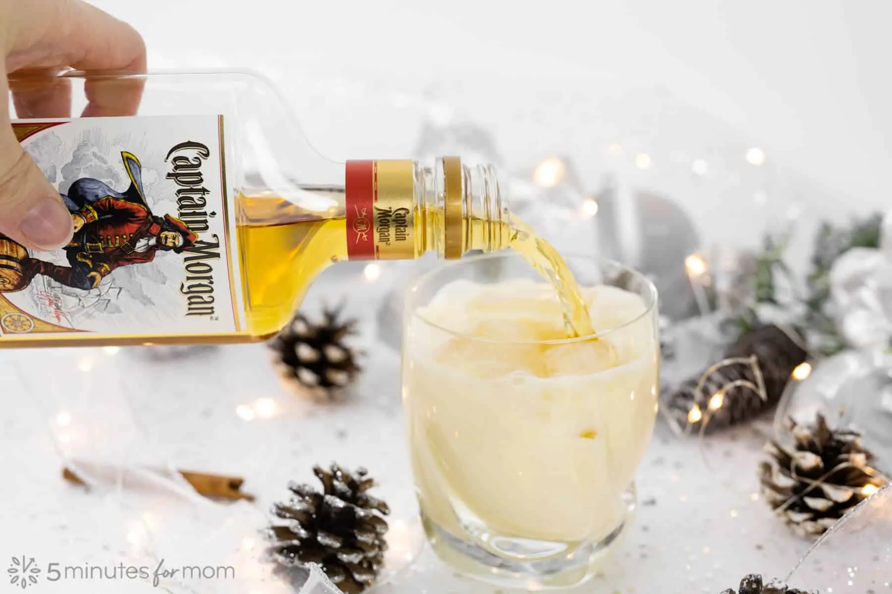 Pouring spiced rum into homemade eggnog