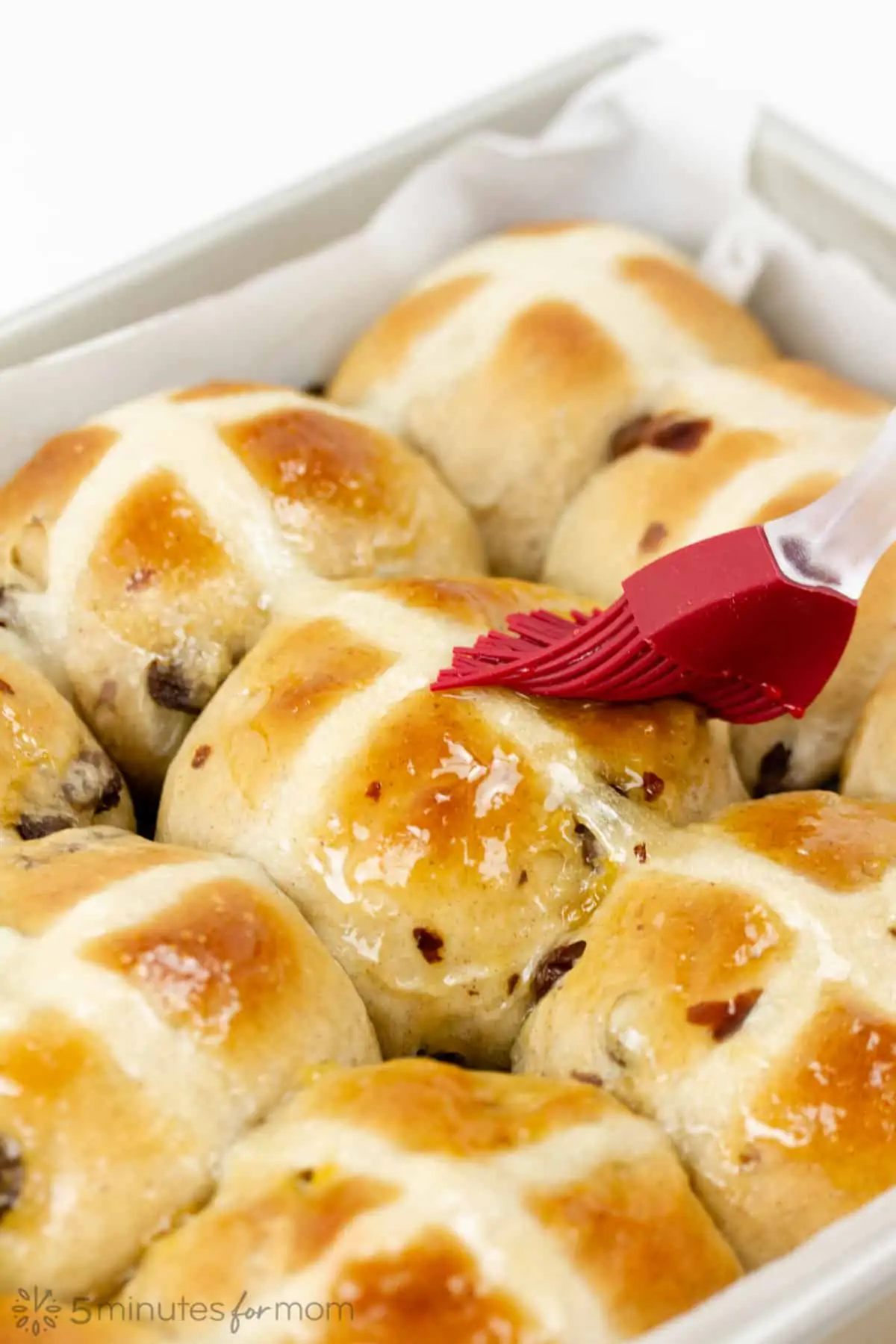 apricot jam syrup glaze brushed on the top of hot cross buns