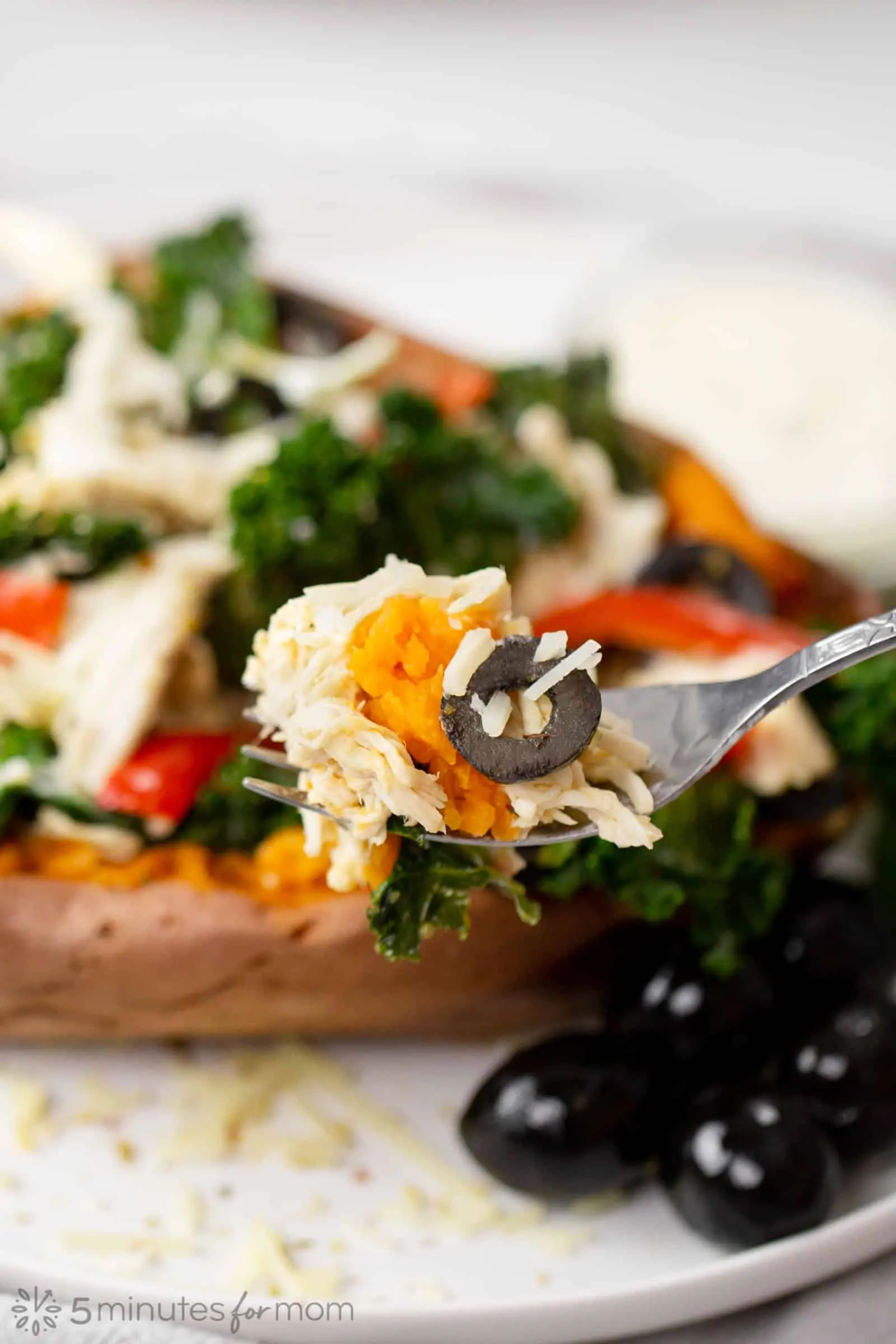a forkful of stuffed sweet potatoes with shredded chicken and black olives