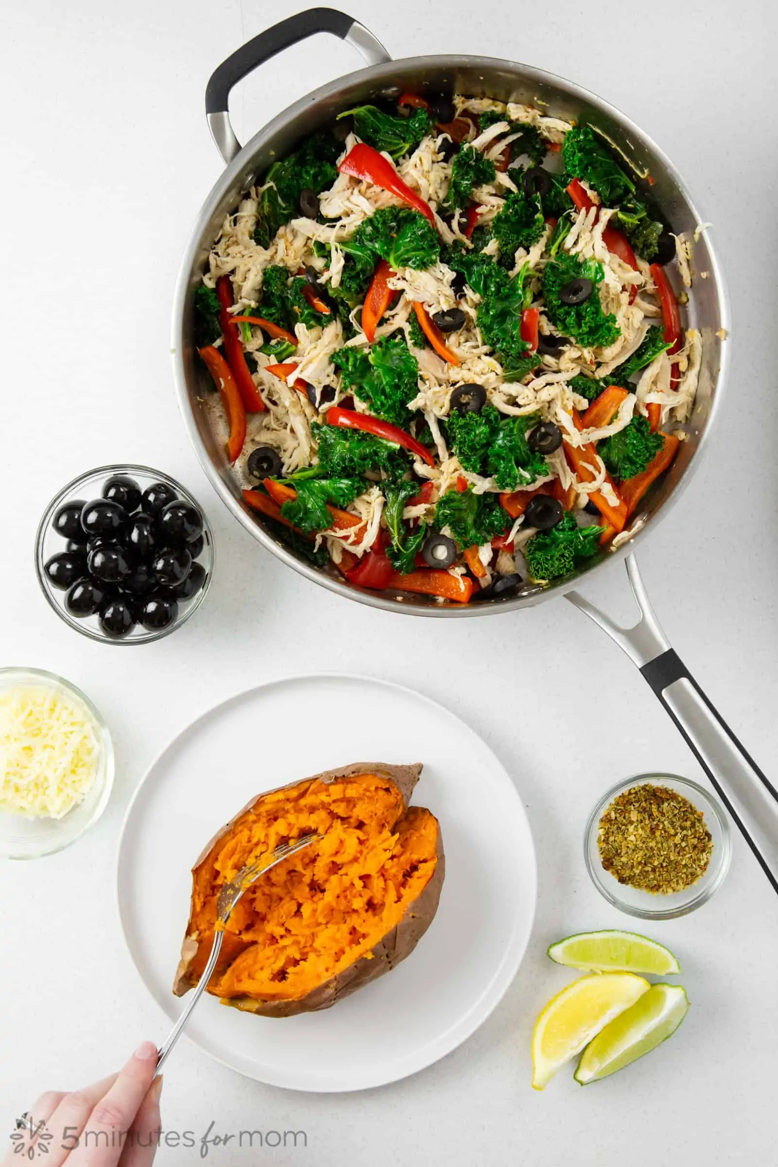 a baked sweet potato with toppings including olives, cheese, vegetables, and herbs