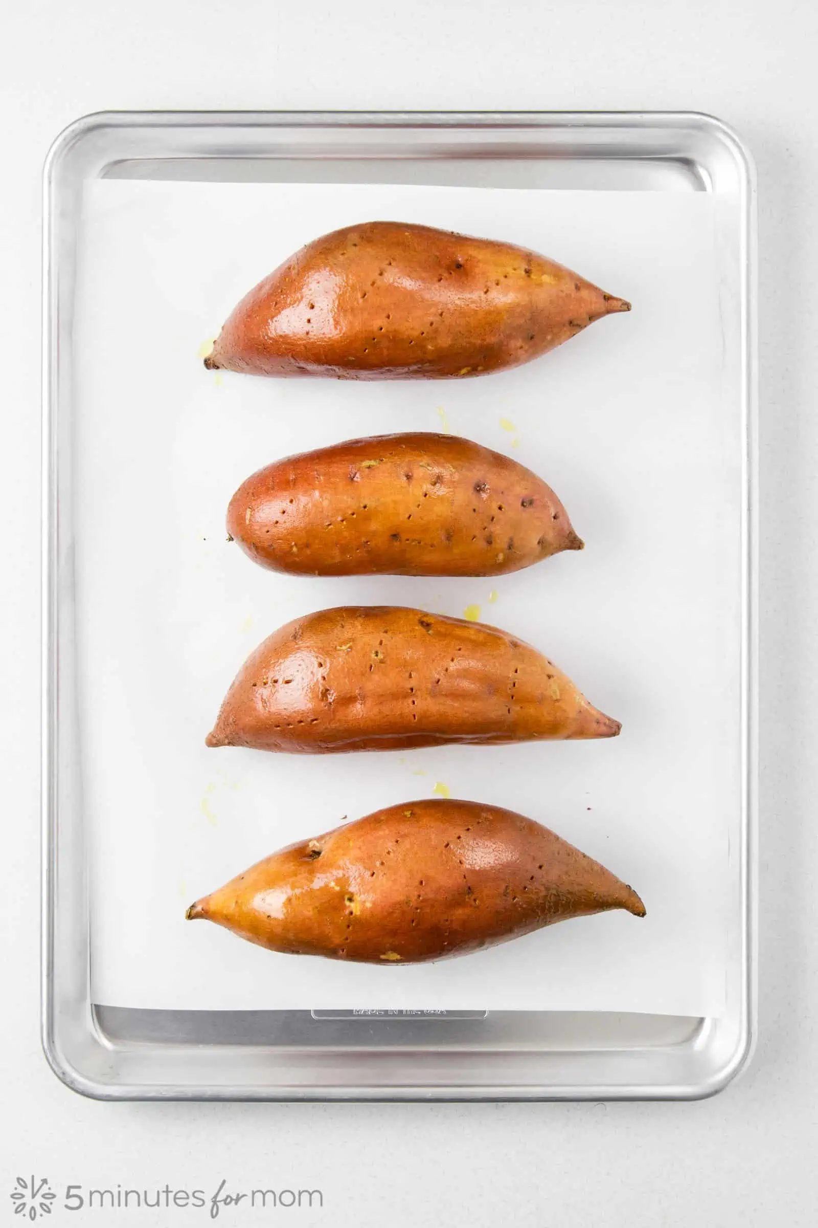 sweet potatoes ready to go into the oven that are covered in olive oil and pierced with a fork