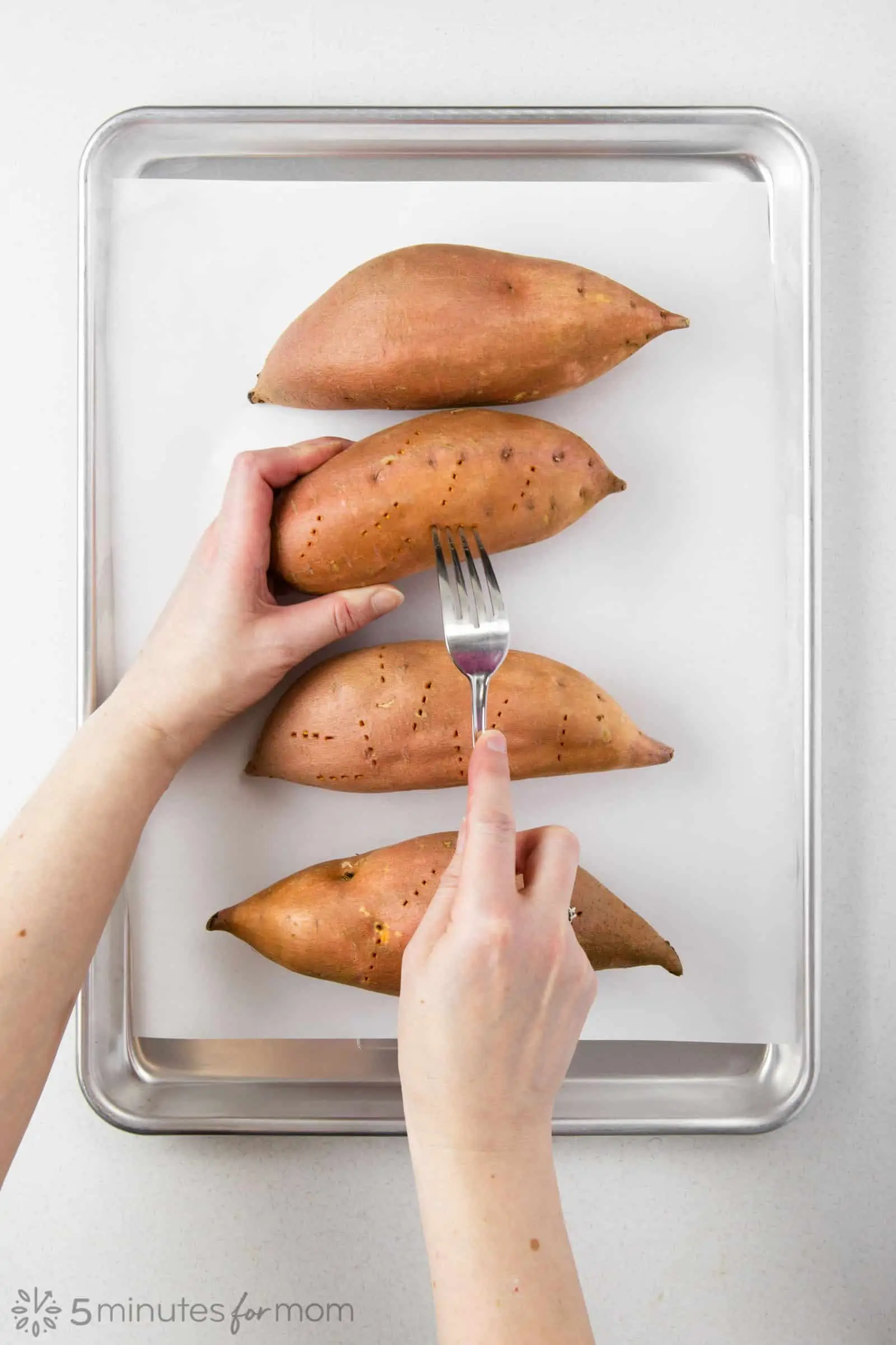 piercing holes with a fork into sweet potatoes