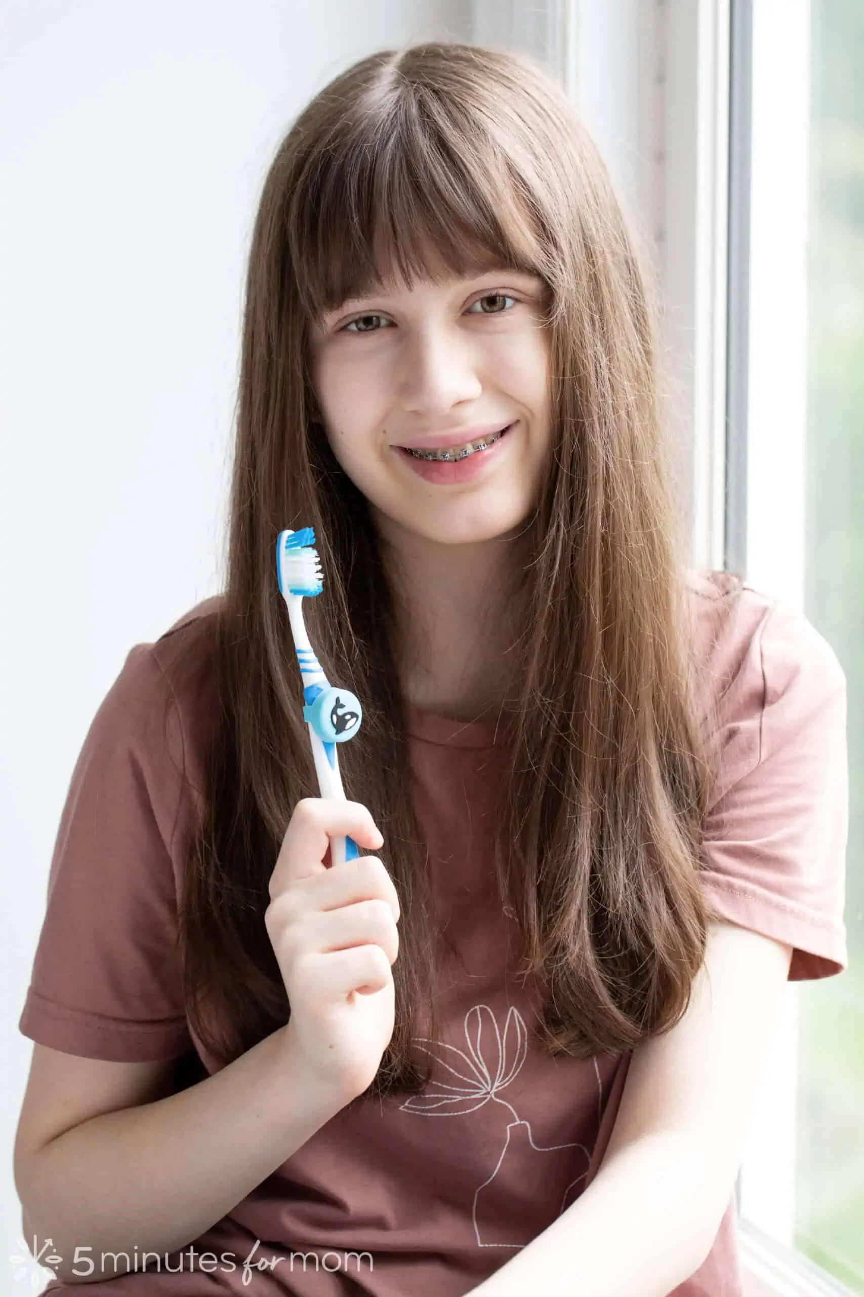 Girl showing a toothbrush with a Truthbrush tracker on it